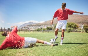 Men, soccer and slide tackle in sports fitness, training and exercise on the field outdoors. Athlet